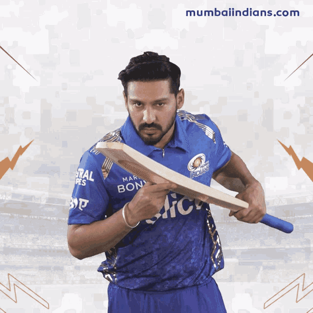 a man in a blue mumbai indians jersey holds a cricket bat