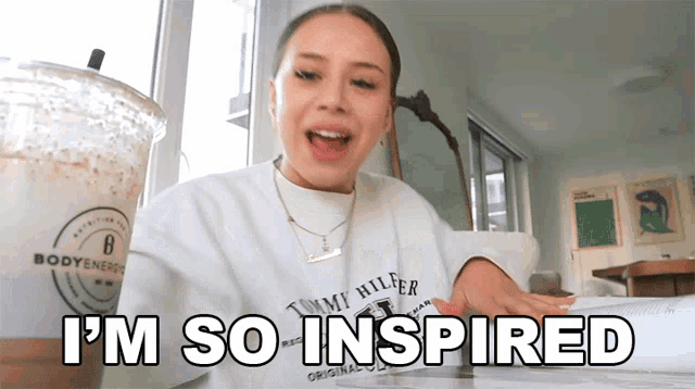 a woman wearing a tommy hilfiger sweatshirt is sitting at a table