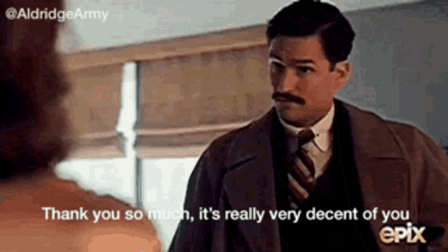 a man with a mustache is talking to a woman in a room .