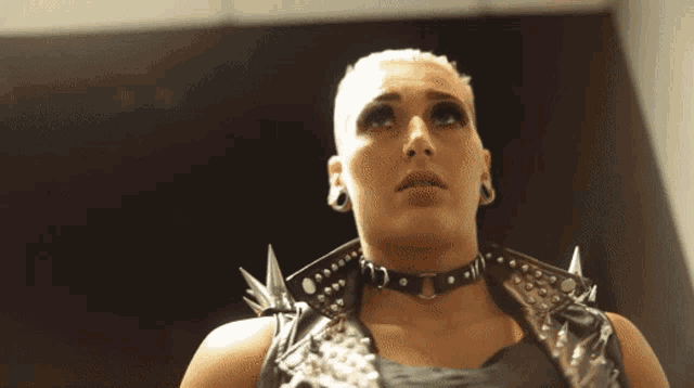 a woman wearing a choker and a leather vest with spikes