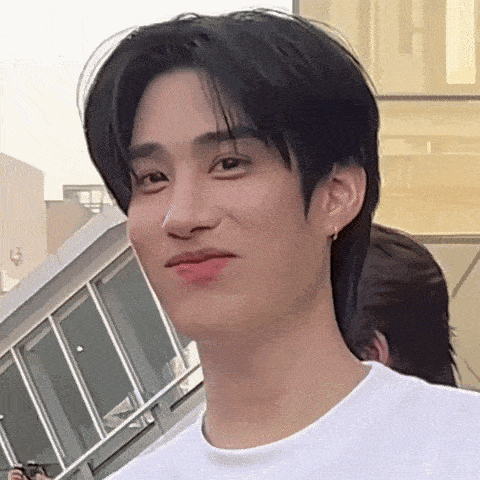 a young man wearing a white shirt is making a face