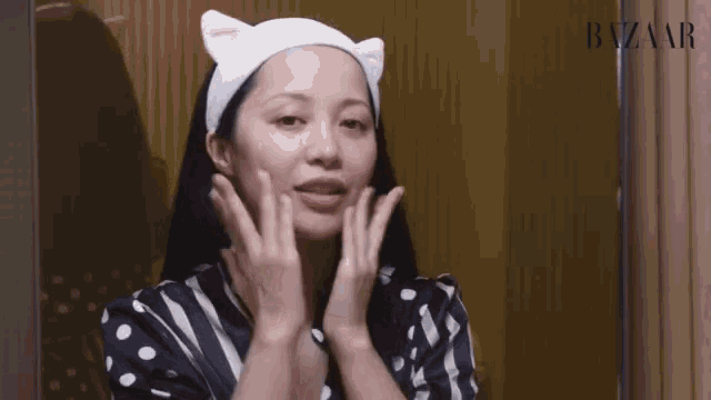 a woman wearing a headband with cat ears is looking at her face