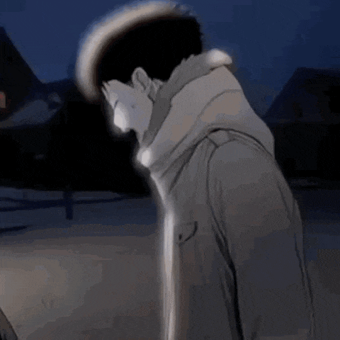 a man in a trench coat is standing in the dark .