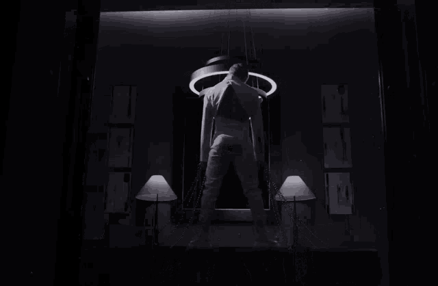 a black and white photo of a person standing in front of a circle light
