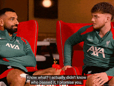 two men are sitting in red chairs and one of them is wearing a green shirt that says ' axa ' on it