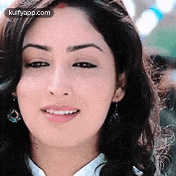 a close up of a woman 's face with a smile on her face and earrings .