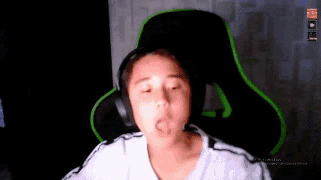 a young boy wearing headphones is sitting in a chair with his mouth open