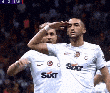 a soccer player wearing a sixt shirt salutes