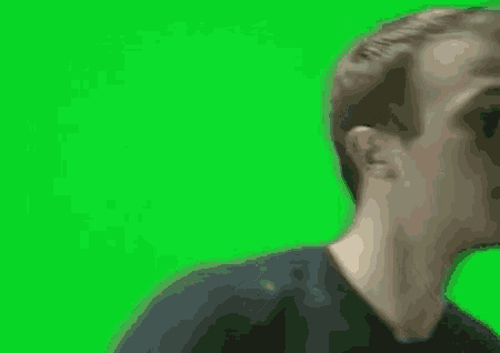 a man in a black shirt is looking at the camera on a green screen .