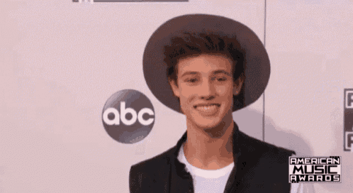 a young man wearing a hat is smiling in front of an abc logo