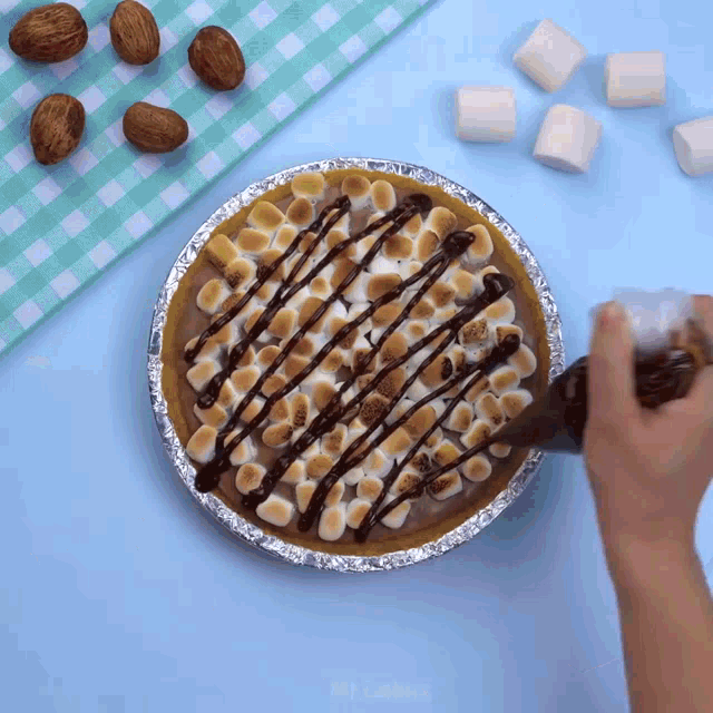 a s'mores pie is being decorated with chocolate drizzle and marshmallows