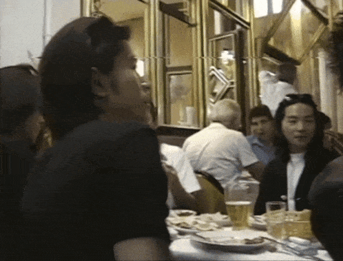 a group of people are sitting at a table with plates and glasses of beer