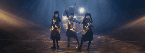 three women are dancing in front of a disco ball in a dark room