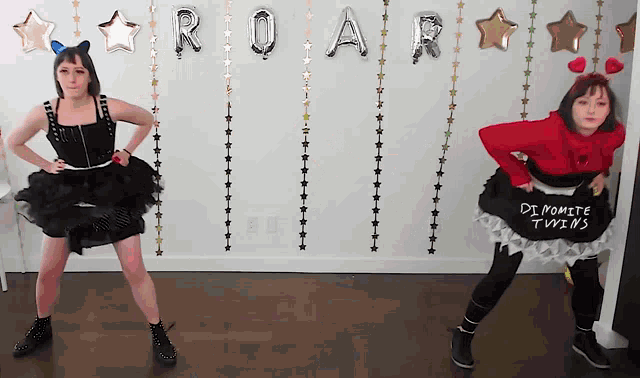 two women are dancing in front of balloons that say roar and dynamite twins