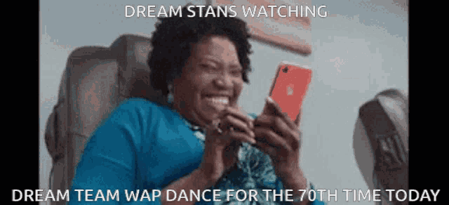 a woman is smiling while looking at her cell phone with the caption dream stans watching dream team wap dance for the 70th time today