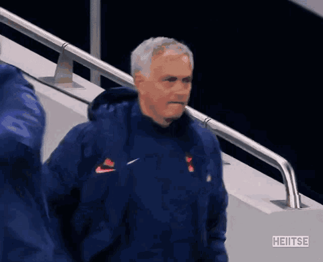 a man wearing a blue nike jacket is walking down stairs