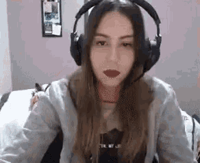 a woman wearing headphones is sitting in front of a bed .