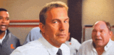 a man in a white shirt and tie is standing in front of a group of people .