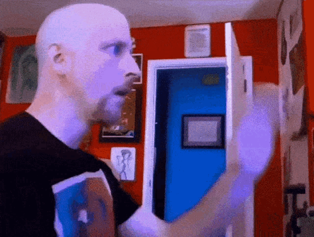 a bald man is standing in front of a door