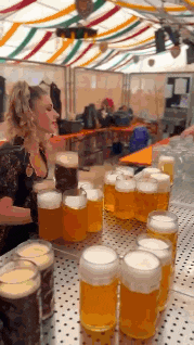 a woman is standing behind a table full of beer glasses