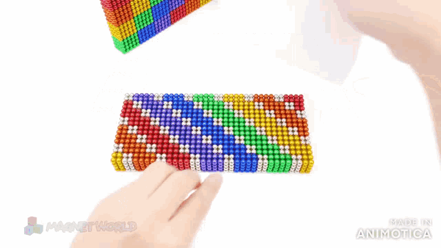 a person is playing with a stack of colorful magnets made by magnetworld