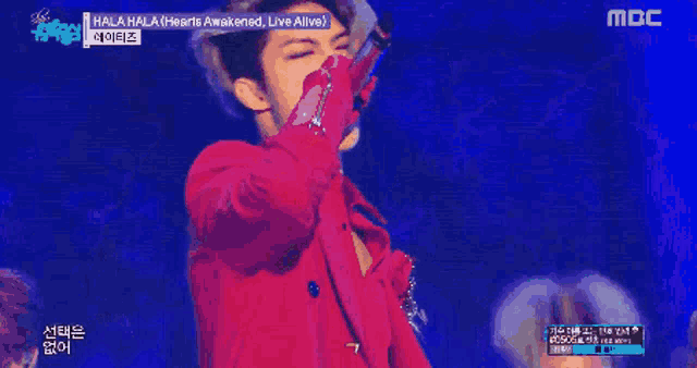 a man in a red coat is standing in front of a group of people on a stage with hearts awakened live alive