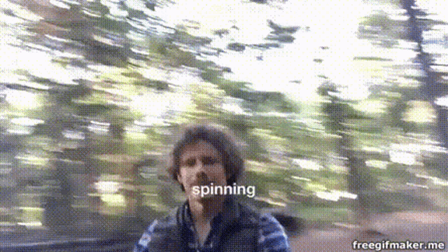 a man in a plaid shirt is spinning in the woods