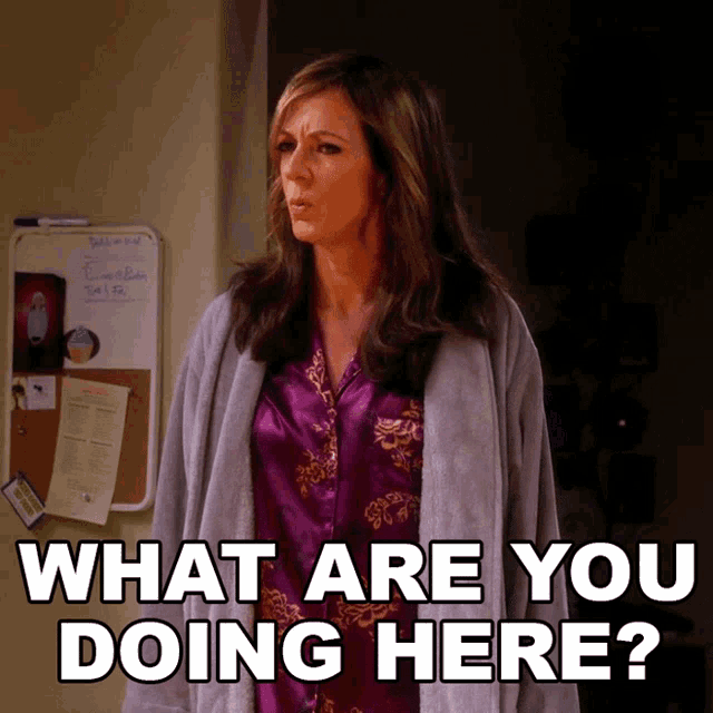 a woman wearing a purple shirt and a grey cardigan says what are you doing here