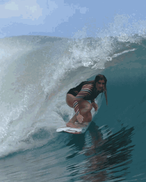 a woman rides a wave on a surfboard in the ocean