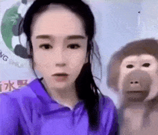 a woman is standing next to a stuffed monkey and taking a selfie .