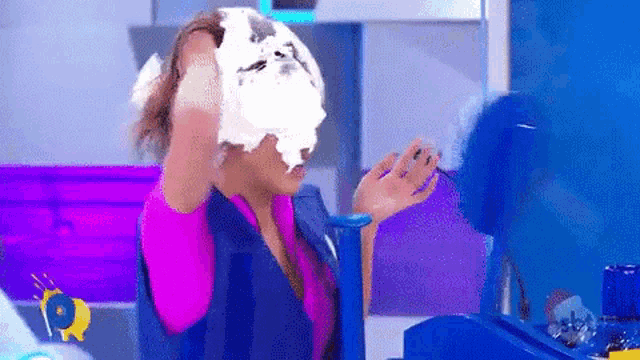 a woman is standing in front of a machine with a piece of cake on her head .