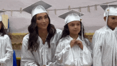 a woman in a graduation cap and gown is standing next to a girl