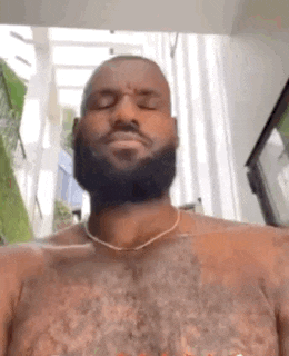a shirtless man with a beard and a necklace on his neck is looking at the camera .
