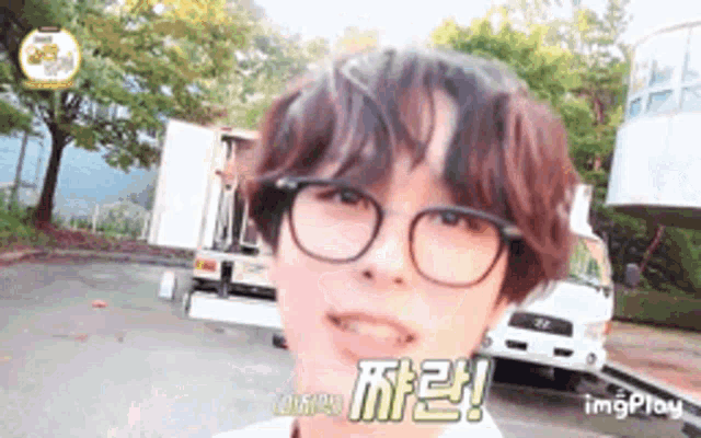 a man wearing glasses is standing in front of a truck .
