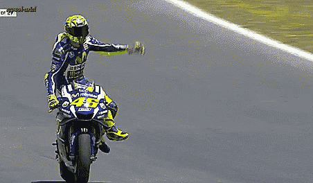 a man is riding a motorcycle on a track and giving a thumbs up .