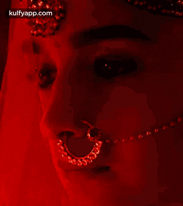 a close up of a woman 's face with a nose ring and a necklace