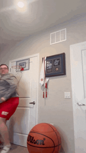 a wilson basketball sits on the floor in front of a man playing basketball