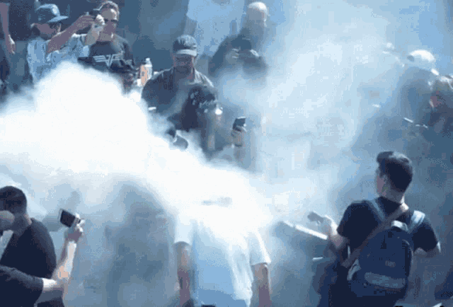 a group of people are standing in a room with smoke coming out of it and one of them is wearing a vans hat