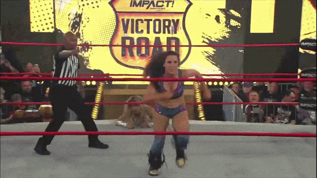 a woman in a wrestling ring with a sign that says impact