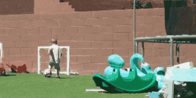 a green rocking horse with a blue swan on it is on a grassy field