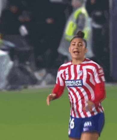 a woman wearing a red and white striped shirt that says herbalife nutrition is running on a soccer field
