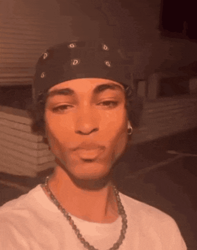 a young man wearing a bandana and a necklace .