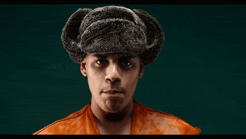 a man wearing an orange shirt and a fur hat