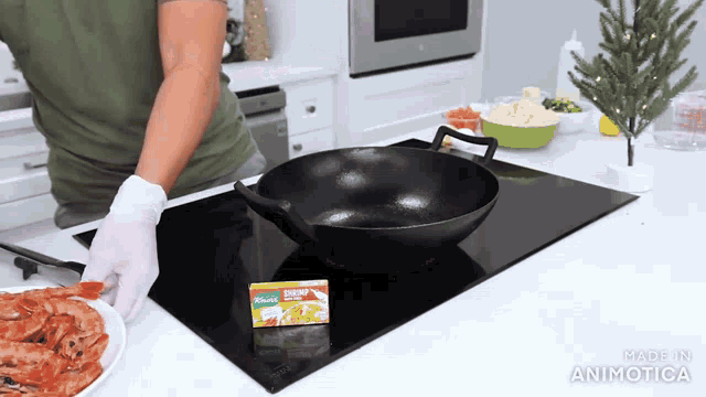 a box of shrimp seasoning sits next to a wok on a stove top