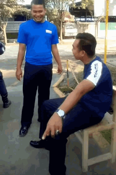 a man wearing a blue shirt that says toyota is sitting on a bench