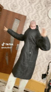 a person in a black coat is dancing with a baby on their back .
