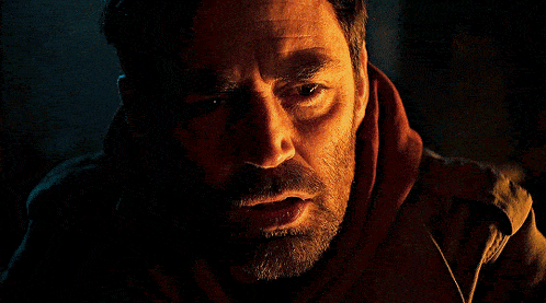 a close up of a man 's face with a beard in a dark room