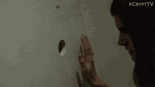 a woman is holding a piece of paper in her hand while looking through a window .