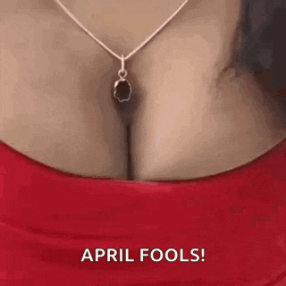 a woman wearing a red top and a necklace with a pendant on her breast .