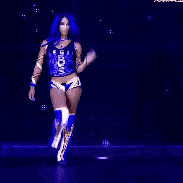 a female wrestler with blue hair is walking on a stage .